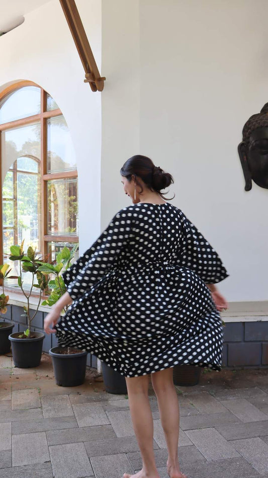 Back view of black polka dot satin dress with relaxed fit