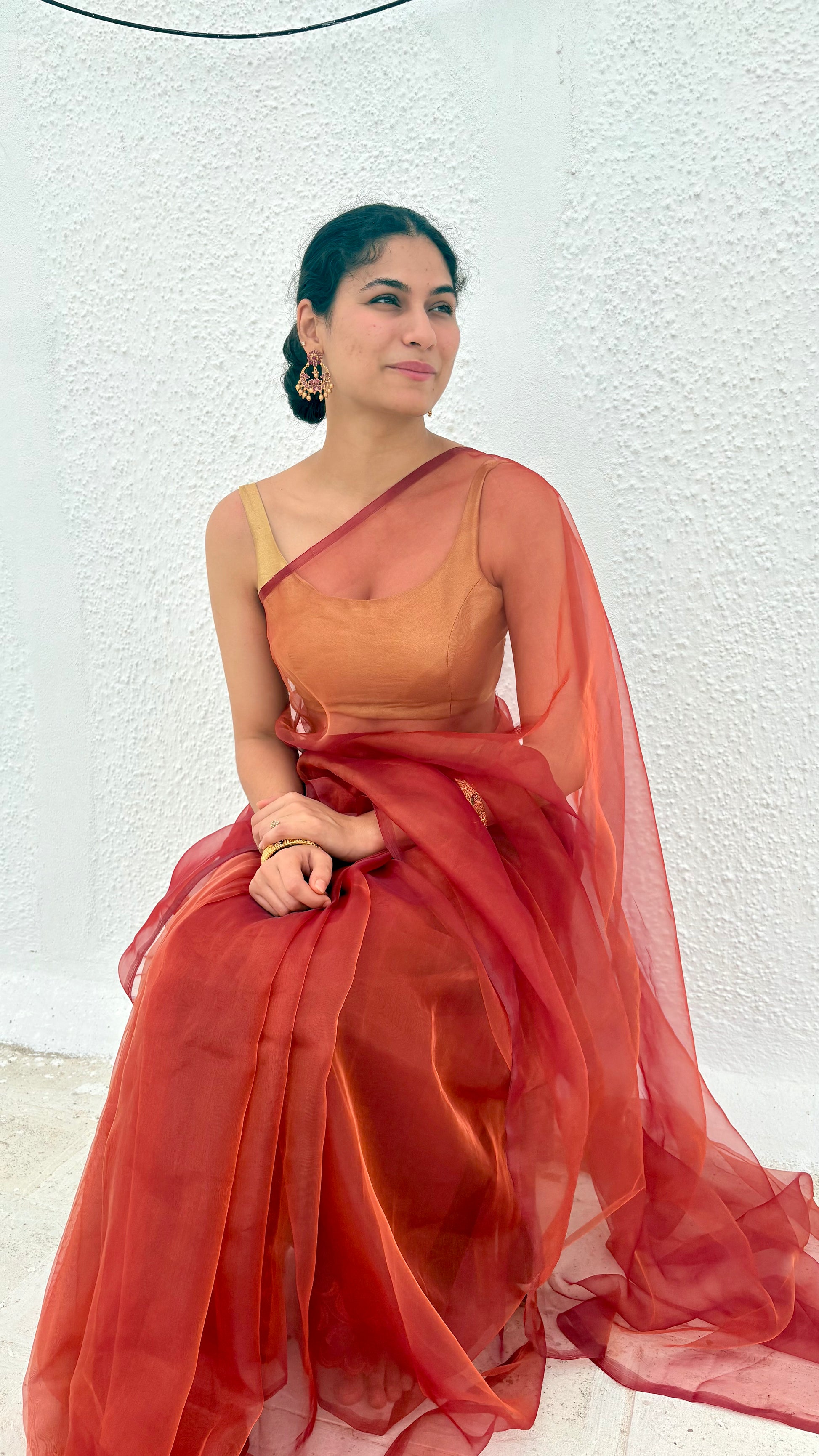 model wearing red maroon orange pink and gold shade organza saree
