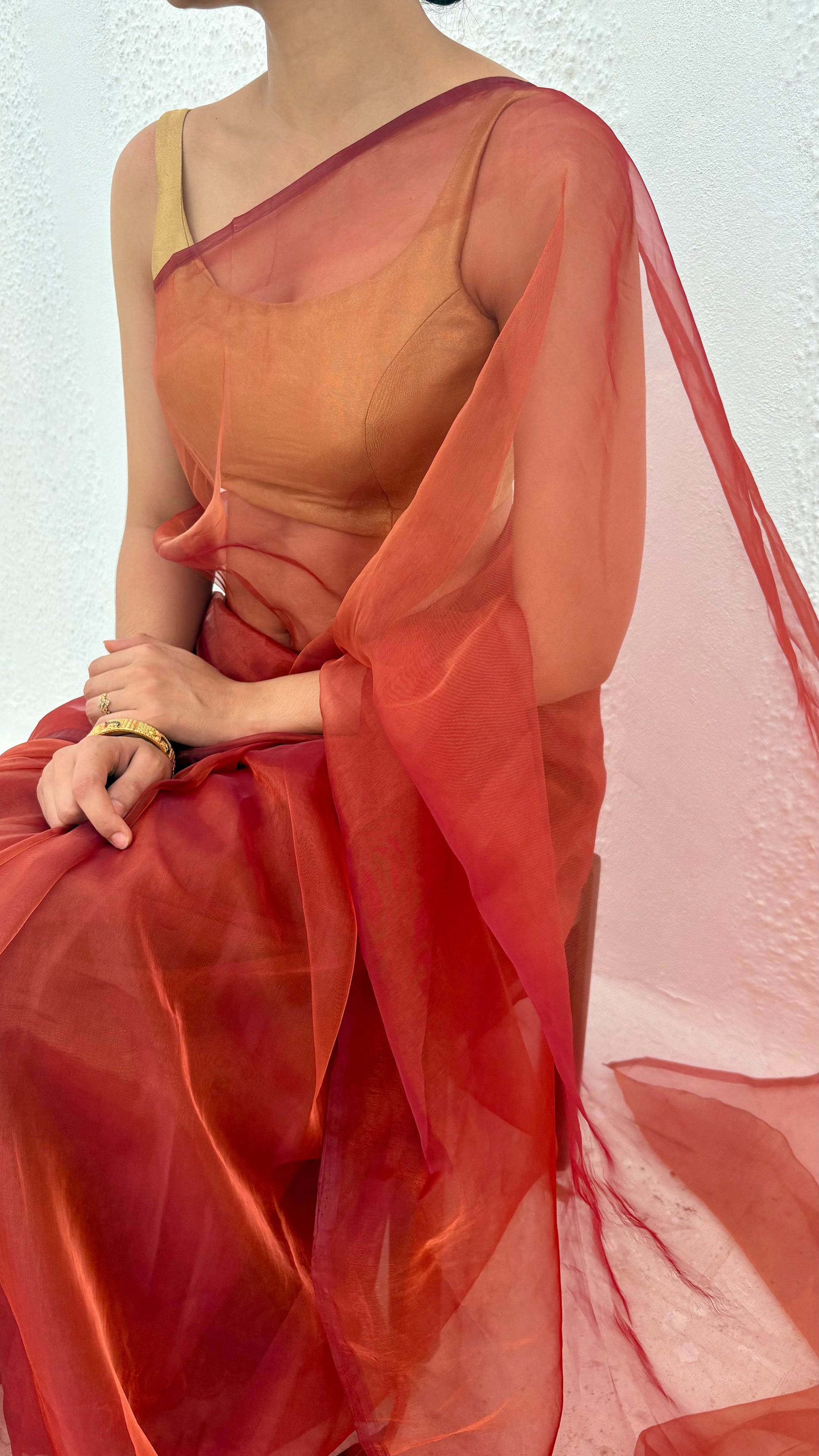 person  wearing red maroon orange pink and gold shade organza saree