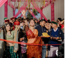 Customers in Queen Bee Honey Organza Saree at a festive event with pink decorations — Label Anaira