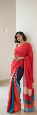 Model wearing scarlet red satin saree with multi-tone pallu in indoor setting