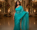 Model wearing sky blue organza saree styled for an evening celebration with warm lights in the background