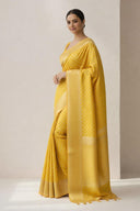 Model wearing Suvarna Aabha Banarasi semi katan-silk saree in golden yellow with traditional Banarasi weave and elegant drape