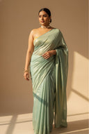Close-up of teal satin silk saree fabric showing gold shimmer and smooth texture